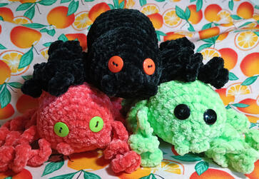 Three crocheted spiders for Halloween: each in different colors - black, orange, and green.